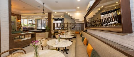 A modern interior with round tables, cushioned seating, and a staircase leading to an upper level.