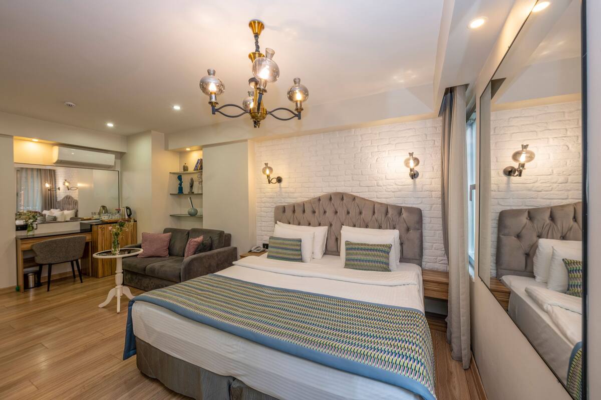 Una habitación de hotel moderna con una cama grande, un escritorio, un sofá y una araña.