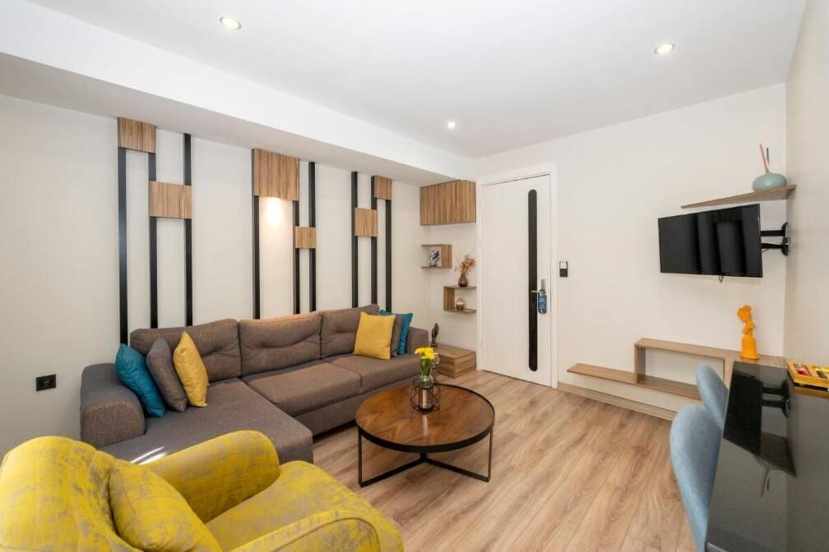 Una sala de estar moderna con un sofá seccional, una mesa de centro y un televisor de pantalla plana montado en la pared.