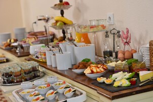 Un bufé con diversos alimentos, incluyendo frutas, carnes, quesos y salsas.