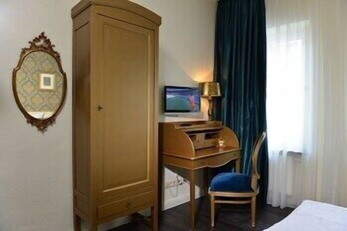 Une chambre d’hôtel avec une armoire en bois, un bureau avec un ordinateur, une chaise et un lit.