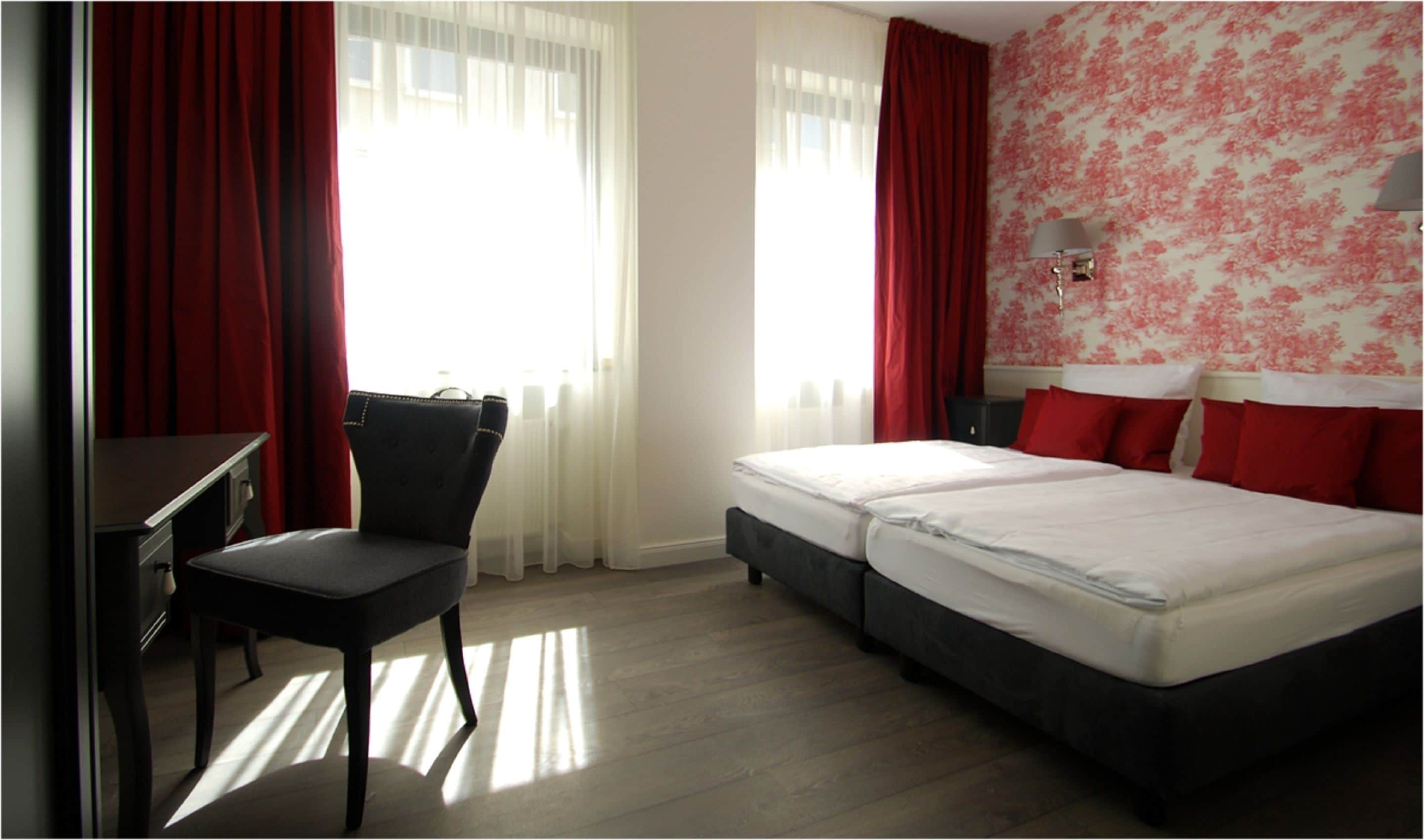 A hotel room with a desk, two beds, and a chair.
