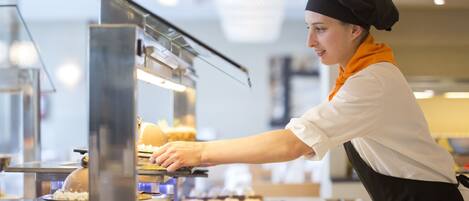 Une personne vêtue d’un uniforme de chef, préparant des aliments dans une cuisine professionnelle.
