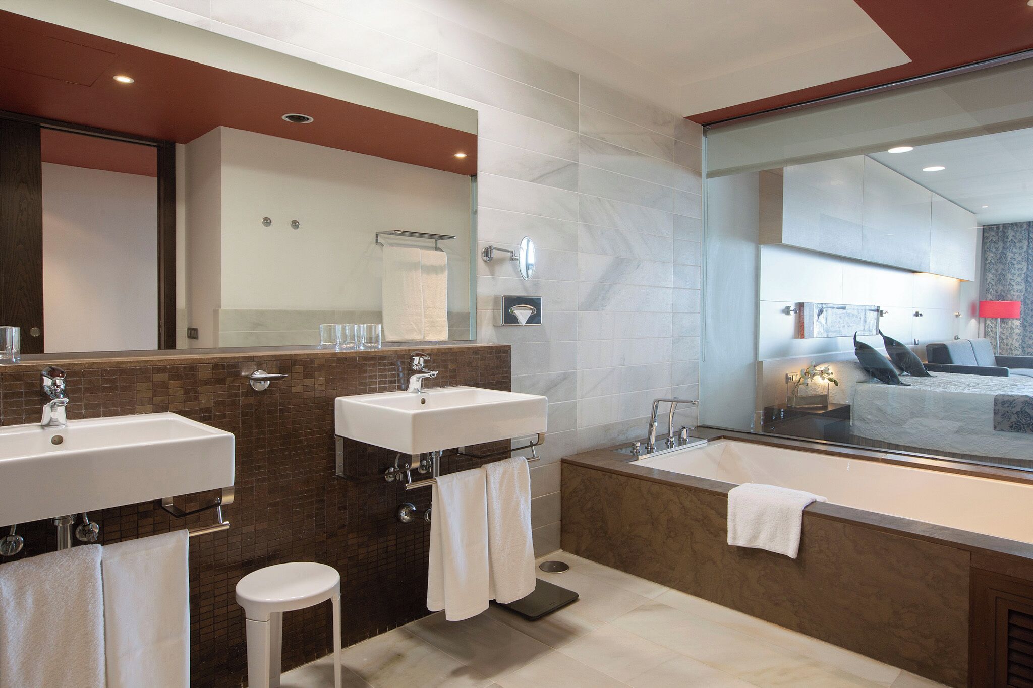 Une salle de bain moderne avec deux lavabos, une grande baignoire et un miroir.