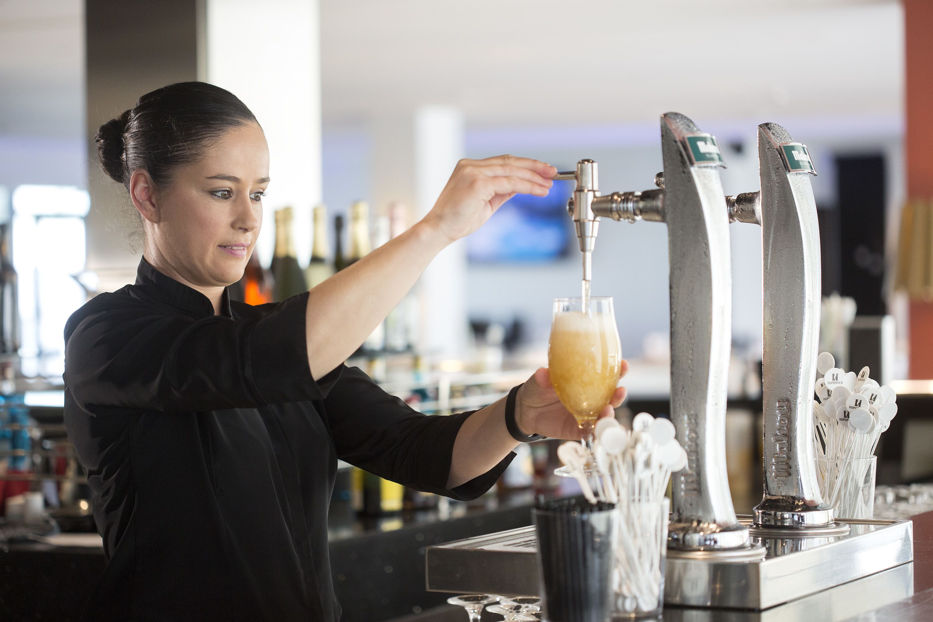 Ein Barkeeper schenkt Getränke aus einem Zapfhahn in ein Glas ein.
