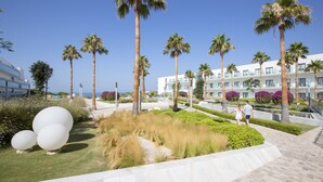 A modern hotel with palm trees, a landscaped garden, and a pool area. - Hipotels Gran Conil (Conil de la Frontera)