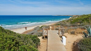 A wooden boardwalk leading to a beach with clear skies and calm sea. - Hipotels Gran Conil (Conil de la Frontera)