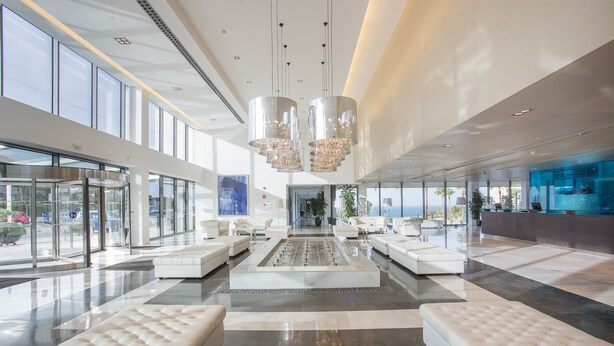 A spacious lobby with a central seating area, large windows, and modern chandeliers. - Hipotels Gran Conil (Conil de la Frontera)