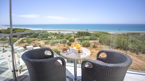 A balcony with wicker chairs, a table with breakfast, and a view of the beach and ocean. - Hipotels Gran Conil (Conil de la Frontera)