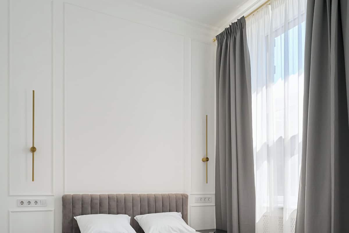 A modern bedroom with a large bed, bedside tables, and a window with curtains.