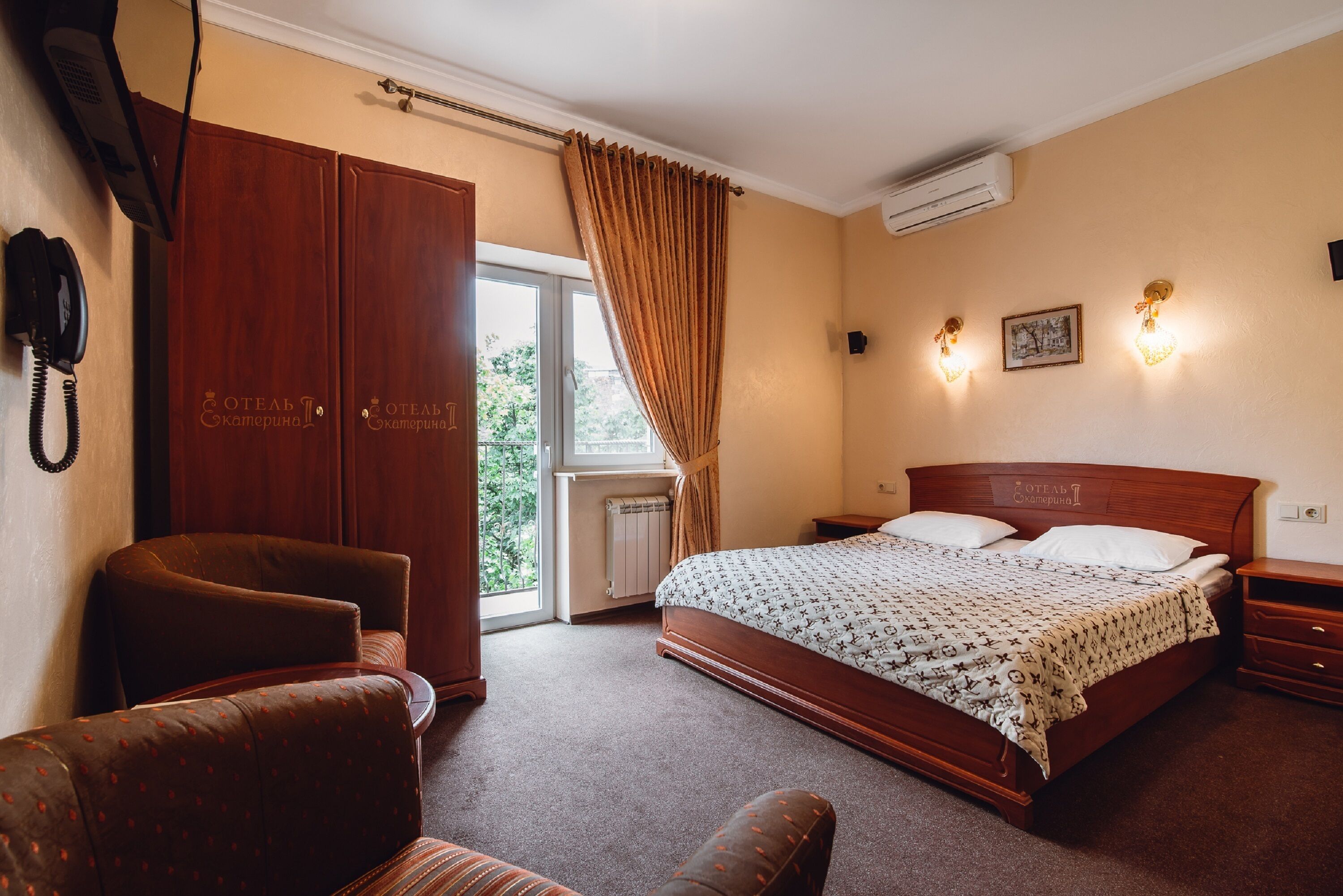 Un dormitorio con una cama grande, un armario de madera, una silla, una mesita de noche y un ventanal con cortinas.