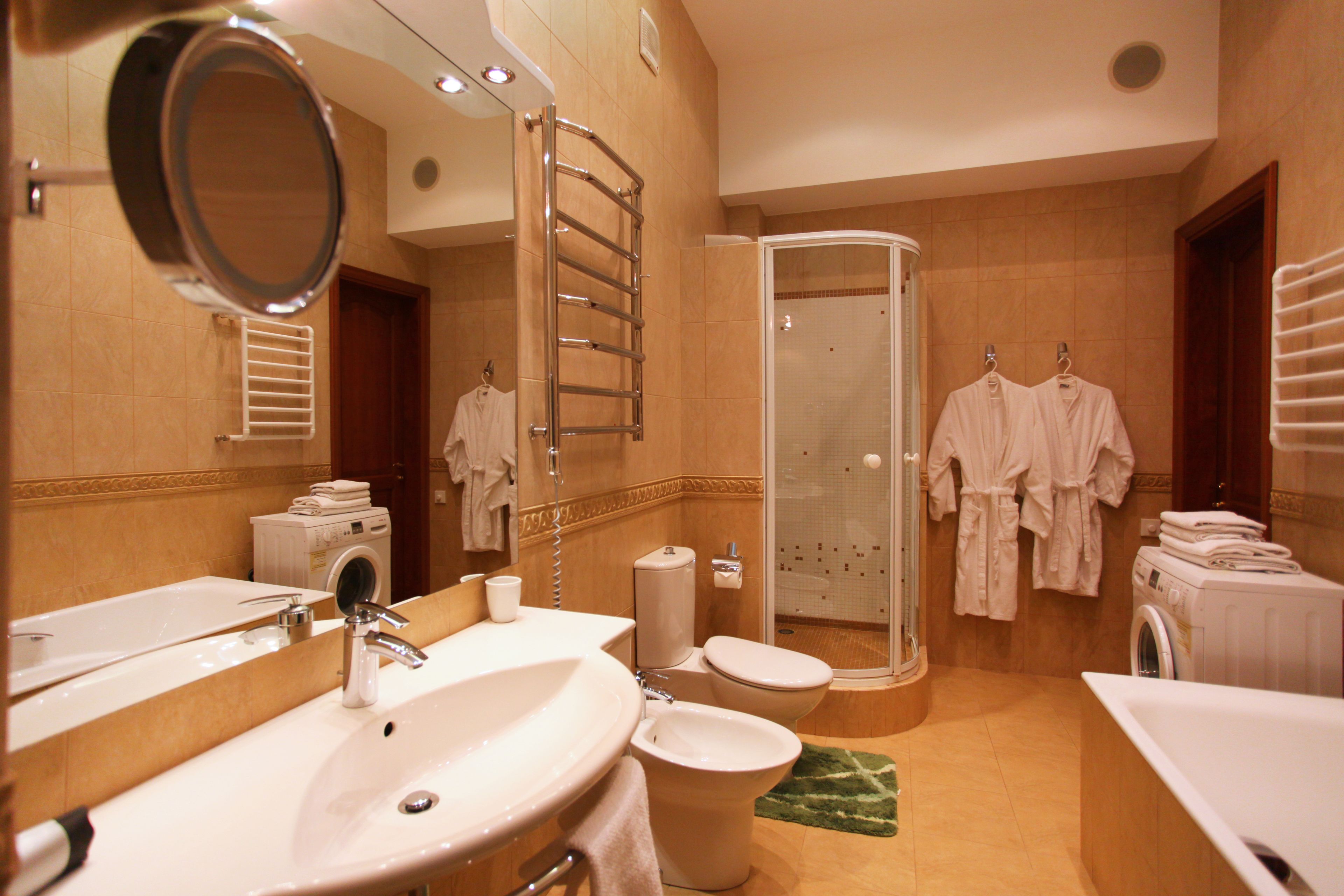 A hotel bathroom with a sink, toilet, shower, and a washing machine.