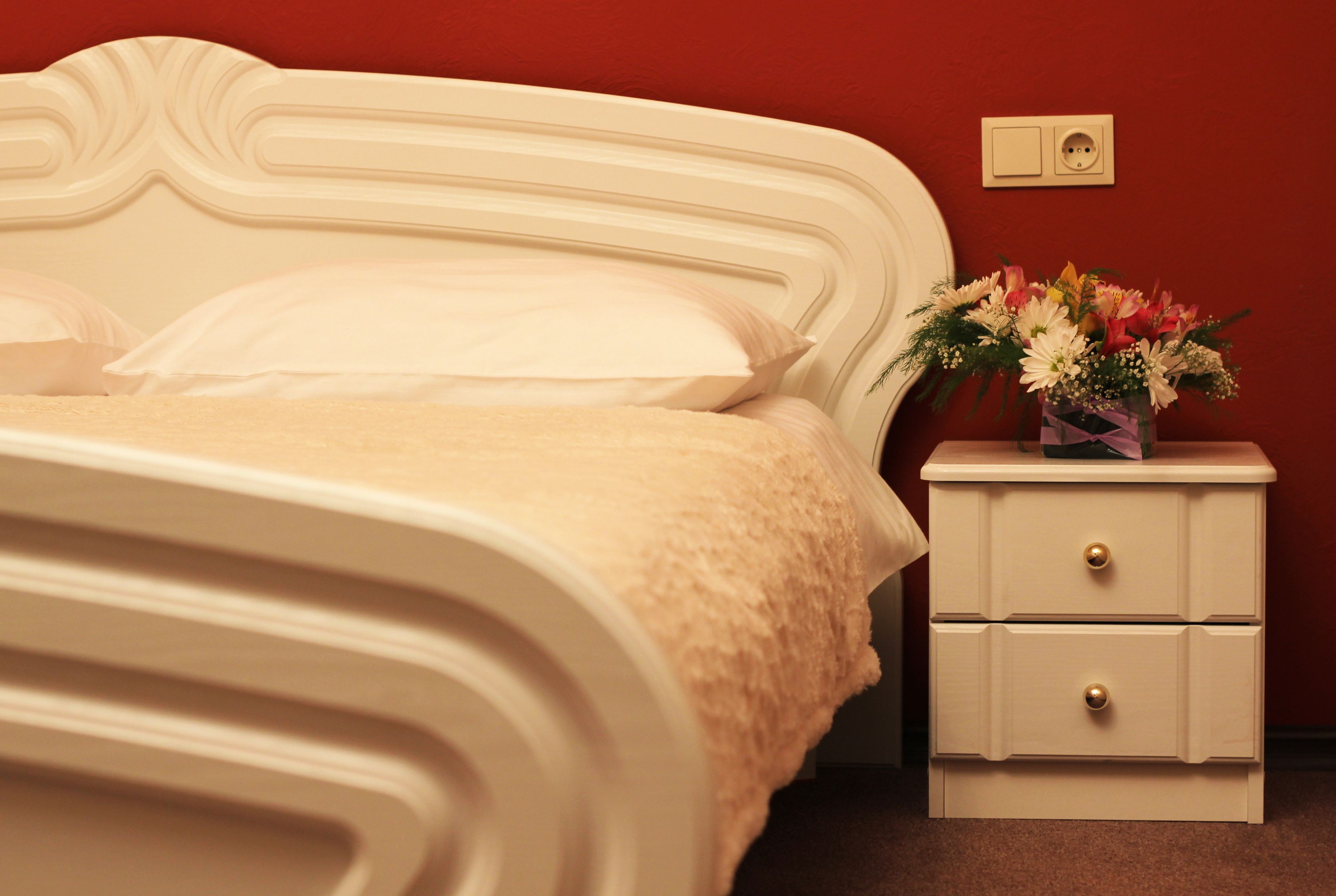 A bed with a white headboard and a nightstand with drawers.