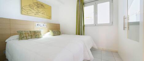 Un dormitorio con cama, ventana y una obra de arte colgada en la pared.