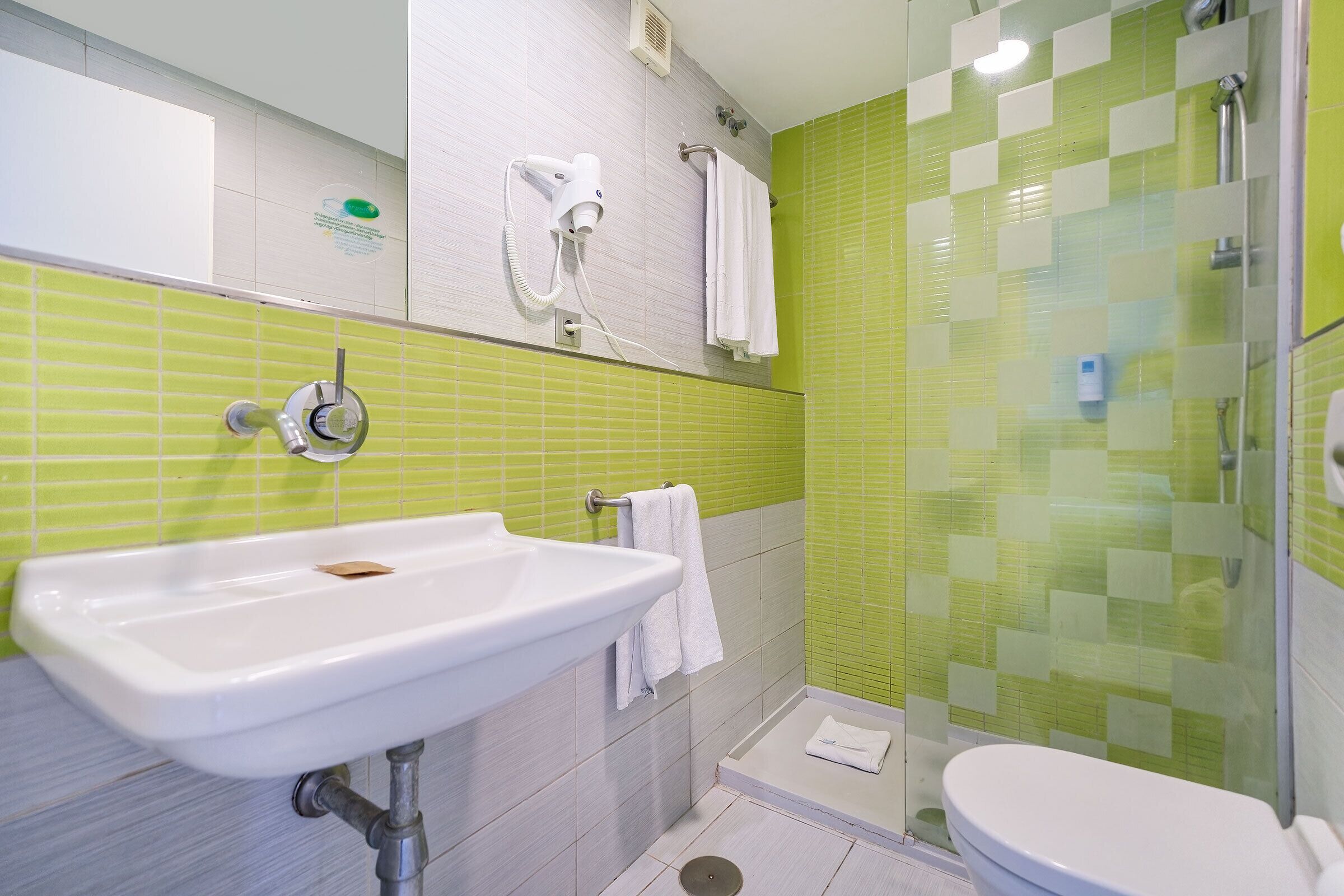 Un baño con lavamanos, inodoro y zona de ducha.