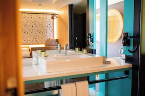 A modern bathroom with a large sink, a towel rack, and a mirror.