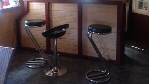 Eine Bar mit Holzvertäfelung, einer Theke und drei Barhocker.