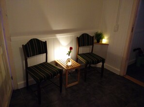 Two striped chairs with a small table and a vase with a single flower between them.
