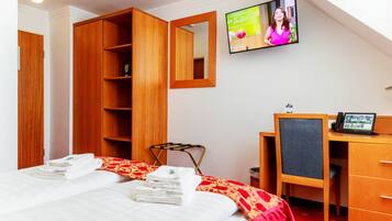 Ein Hotelzimmer mit Bett, Schreibtisch, Stuhl, Fernseher und Kleiderschrank.