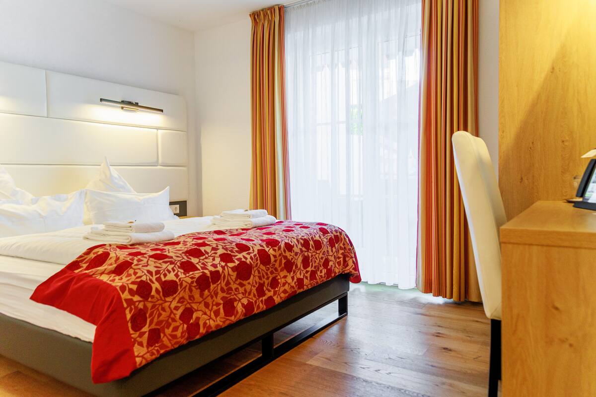 Hotellihuone, jossa on sänky, työpöytä ja tuoli.