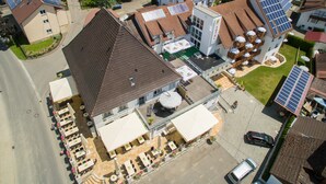 An aerial view of a hotel with a rooftop terrace, solar panels, and a cafe-bar area. - Bodensee-Hotel Kreuz (Uhldingen-Muehlhofen)