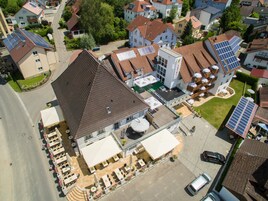 Vista aérea de un hotel con terraza en la azotea, paneles solares y zona de cafetería-bar.