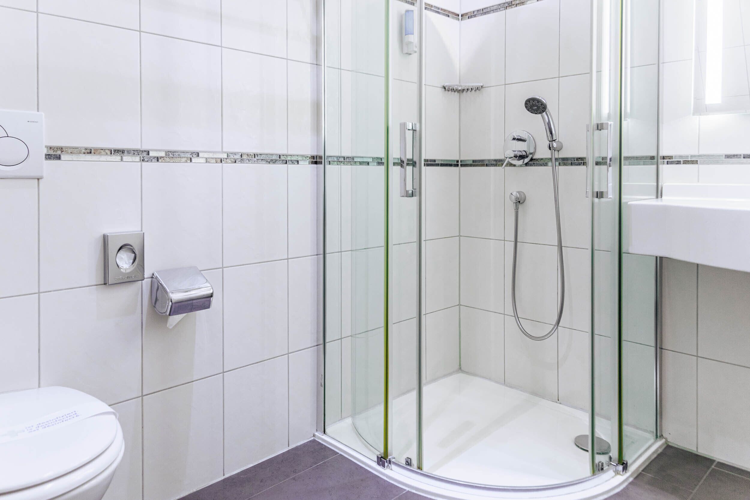 Un baño moderno con ducha vidriada, inodoro y lavamanos.