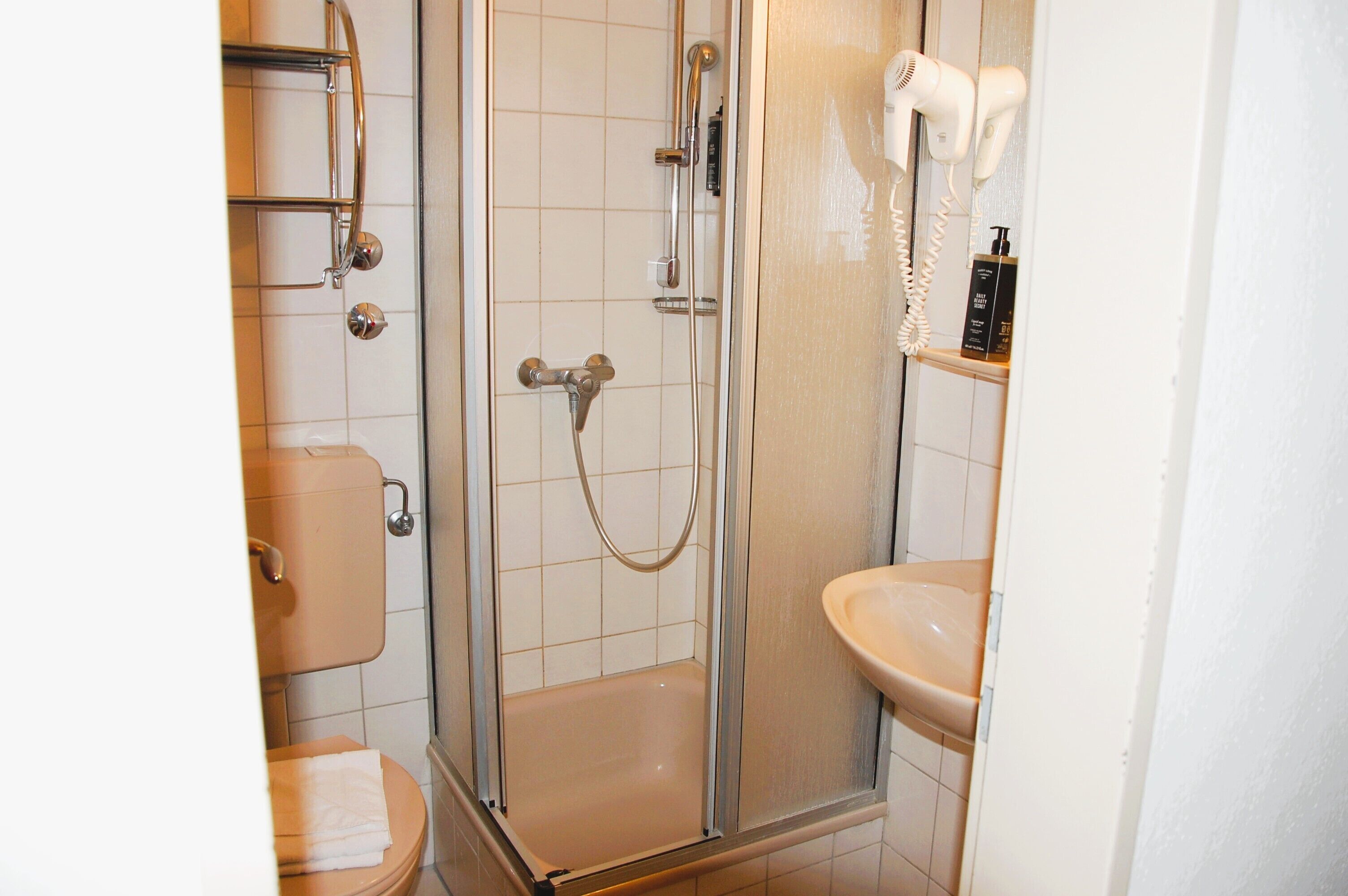 Et badeværelse med en brusekabine i glas, toilet og håndvask.