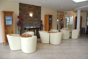 A lobby with a stone wall, a reception desk, and several seating areas with round tables.
