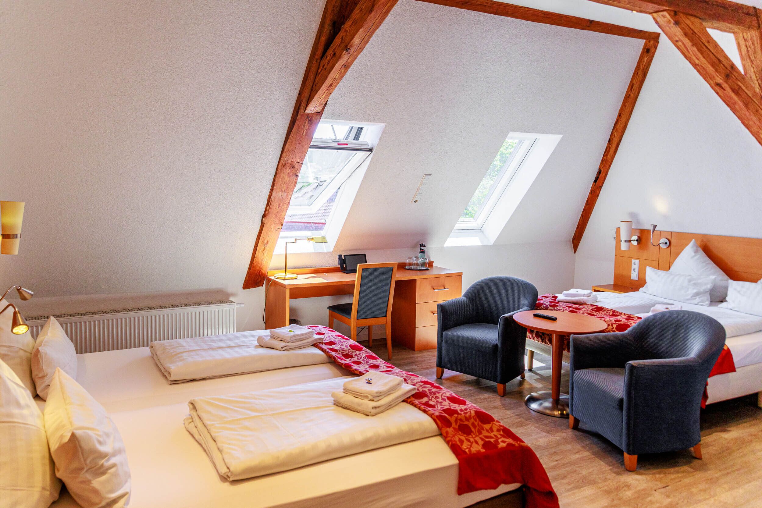A cozy room with a bed, two chairs, a desk, and a small table.