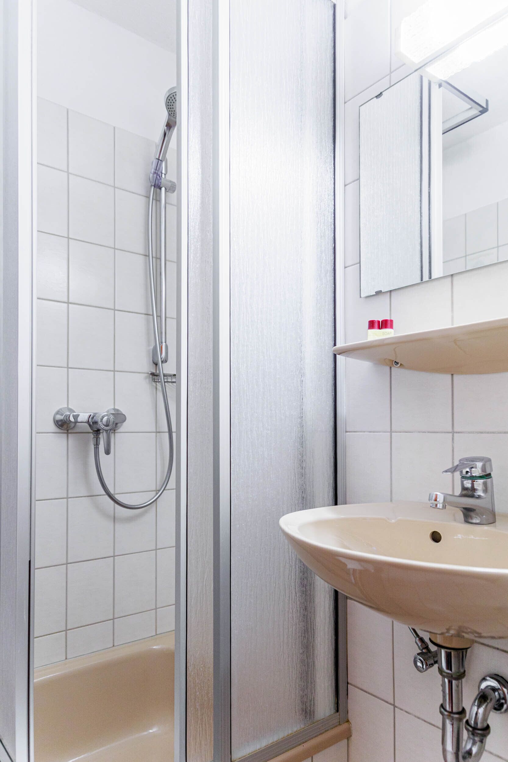Une salle de bain avec une douche, un lavabo et un miroir.