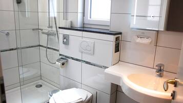 A modern bathroom with a glass-enclosed shower, a toilet, and a sink.