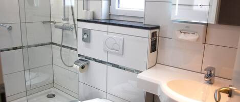 Ein modernes Badezimmer mit einer Glaskabine zur Dusche, einer Toilette und einem Waschbecken.