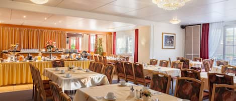 A hotel dining area with multiple tables, chairs, and a buffet setup.
