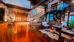 A spacious indoor area with a pool table, seating area with sofas and a rug, a staircase, and a bar area. - Pousada Solar de Búzios (Búzios)
