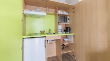 A compact kitchenette with a microwave, coffee maker, and a small refrigerator.