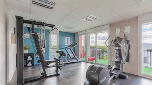 A gym with exercise equipment, a treadmill, and a mirrored wall. - Appart'City Confort Tours (Tours)