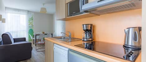 A modern kitchen with a built-in microwave, coffee maker, and kettle.