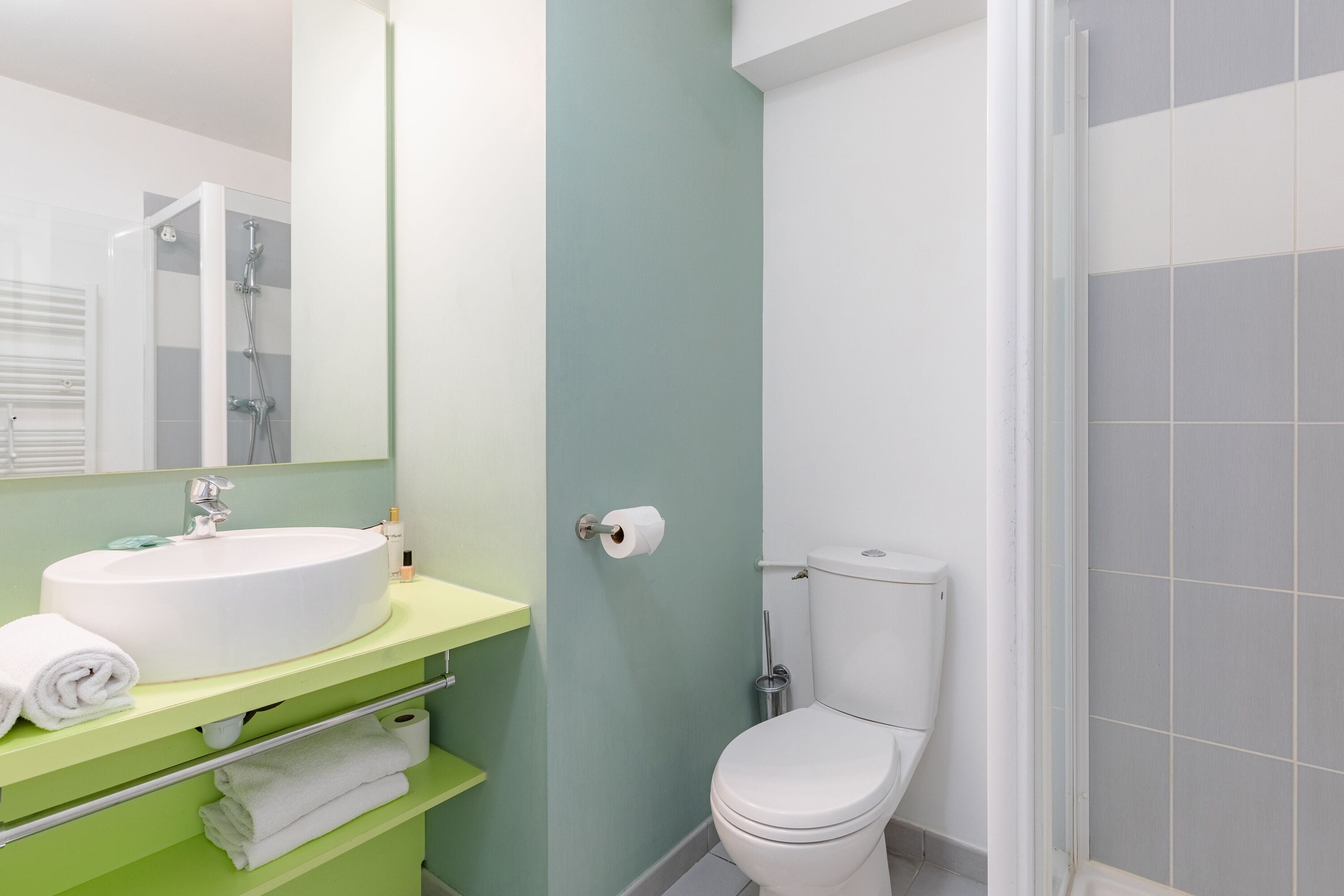 A bathroom with a white sink, green vanity, and a toilet.