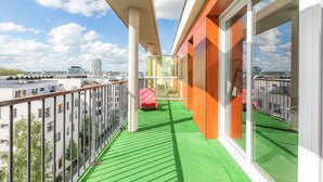 A balcony with a green artificial turf floor, a glass enclosure, and a view of the cityscape. - Appart'City Confort Tours (Tours)