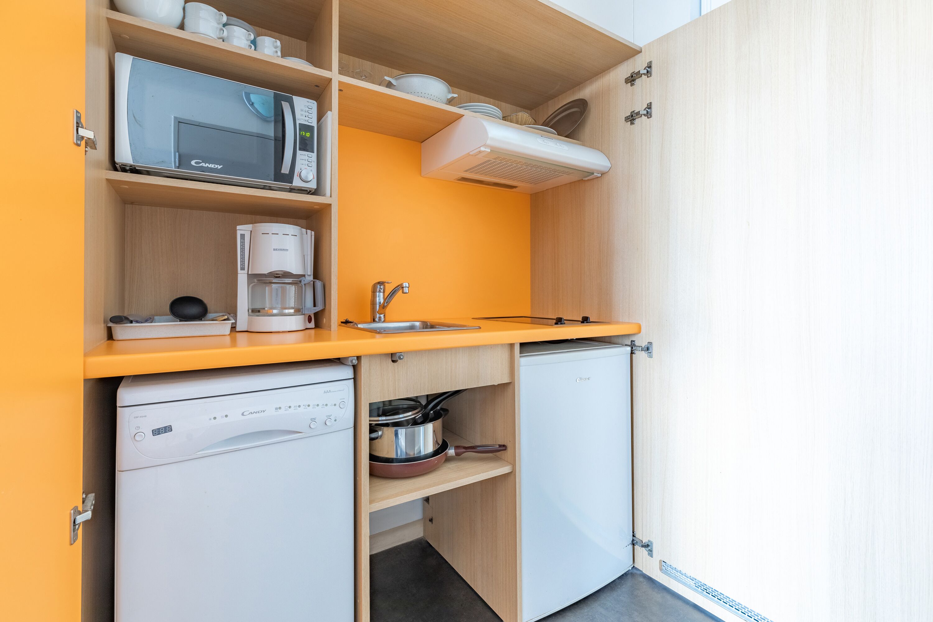 A compact kitchen with a microwave, coffee maker, and dishwasher.