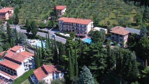 An aerial view of a residential area with multiple buildings, a swimming pool, and surrounding greenery. - Hotel Casa Serena (Malcesine)