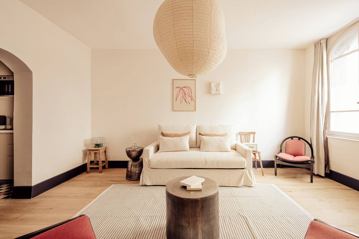A modern bedroom with a large bed, a round coffee table, and a hanging light fixture.