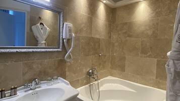 Un baño con bañera, lavamanos y espejo.