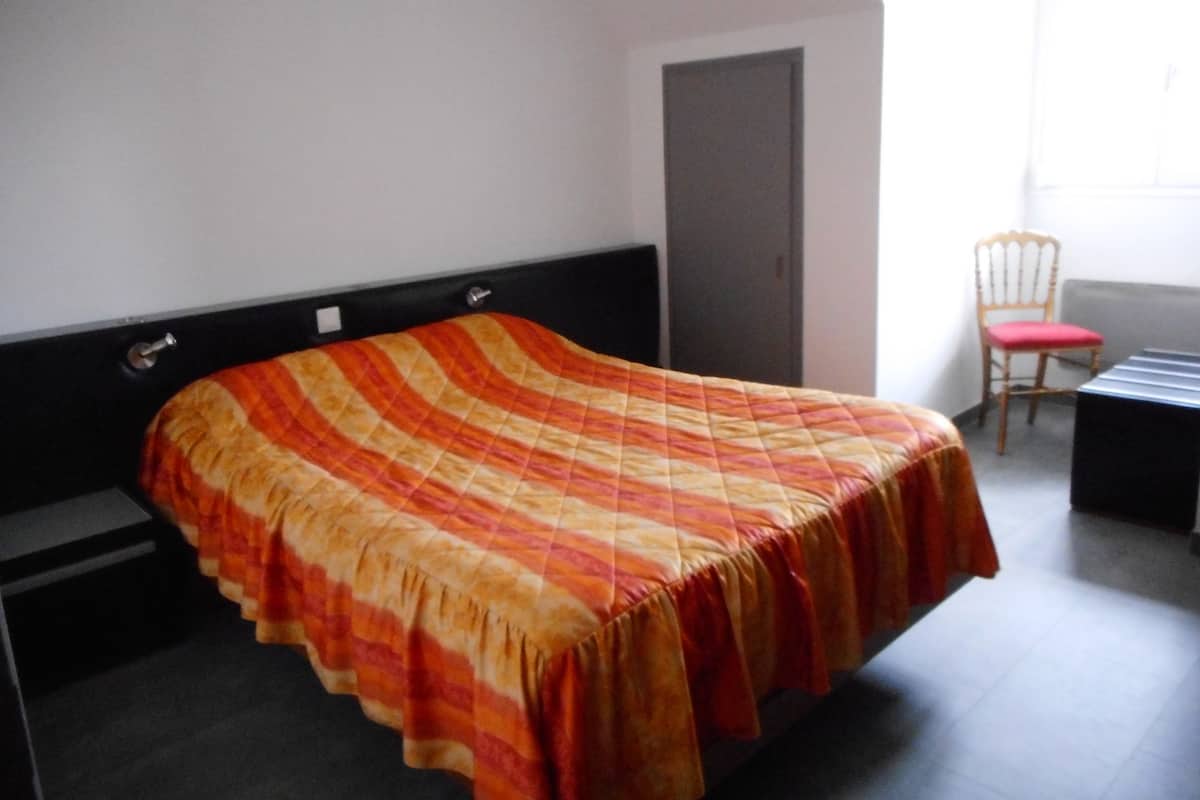 Un lit simple avec une couvre-lit à rayures, dans une pièce qui contient une chaise et un bureau.