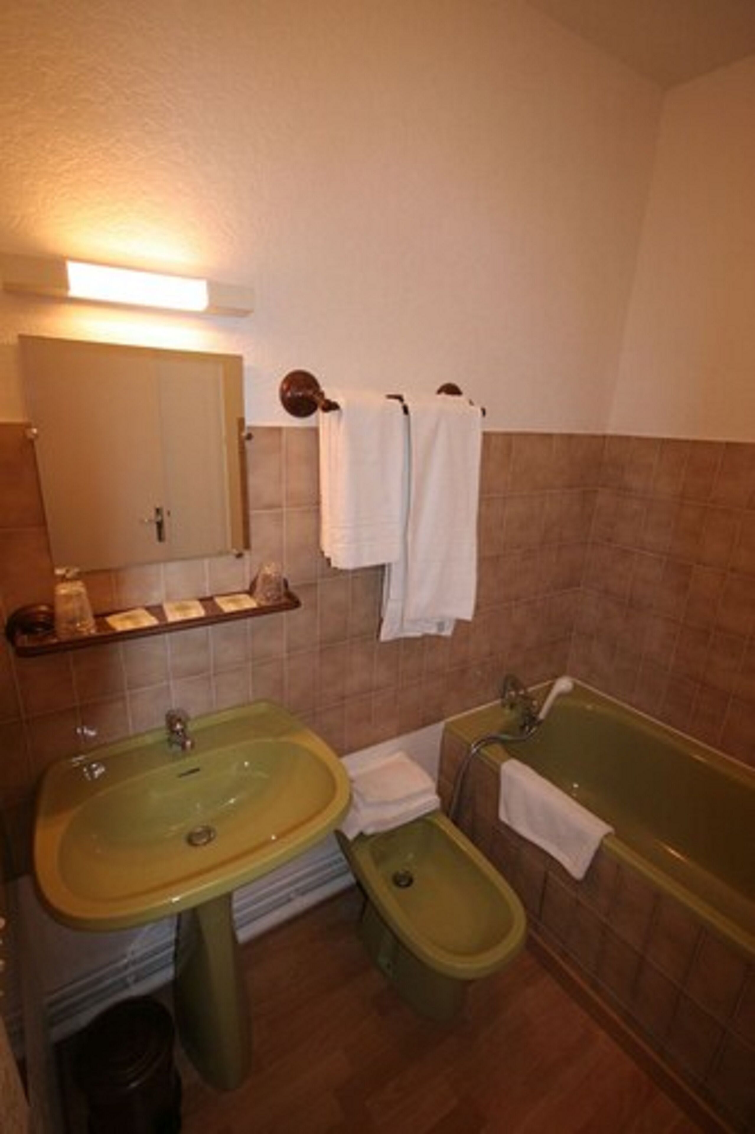 Un baño con un lavabo verde, un bidé, una bañera y un espejo.