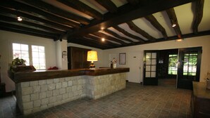 A spacious kitchen with a stone island, wooden beams, and a view of the outdoors. - Hôtel Restaurant La Mangeoire – Relais Paris Bâle (Montieramey)