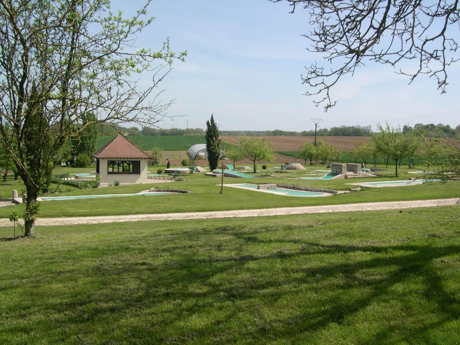 A park with a gazebo, green pathways, and a small building.