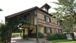 A traditional half-timbered building with a covered entrance and a stone pathway leading to the door. - Hôtel Restaurant La Mangeoire – Relais Paris Bâle (Montieramey)