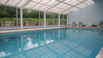 Een binnenzwembad, ligstoelen bij het zwembad